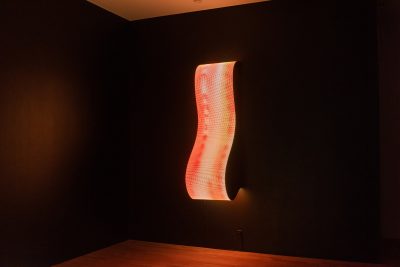 Daniel Canogar Billow V, wavy LED scultpure mounted on black wall emitting red and purple light