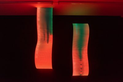 Daniel Canogar Billow IV, two wavy LED sculptures hanging from the ceiling emitting red and green light